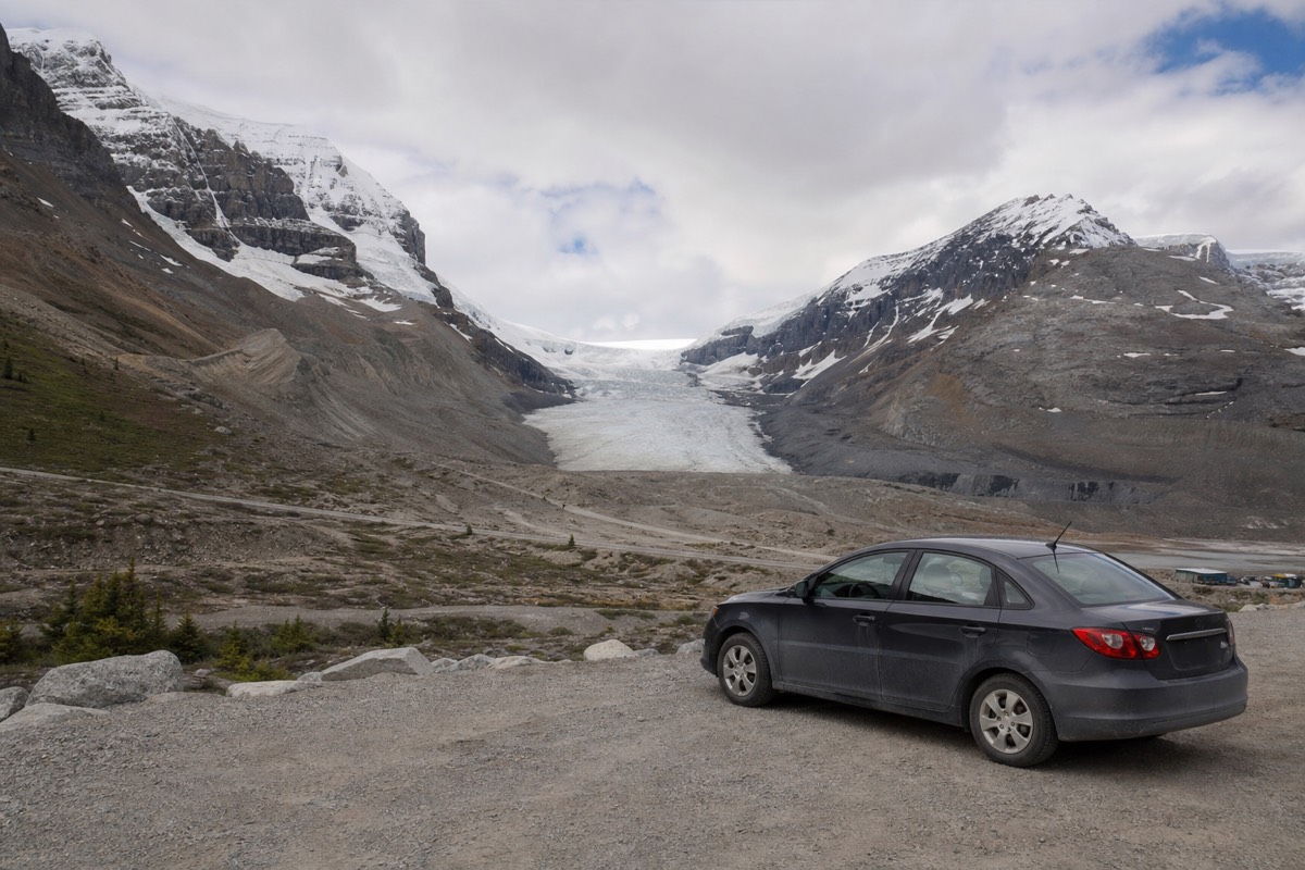 A car at an Icefields Parkway viewpoint with the Athabasca Glacier and Columbia Icefield behind