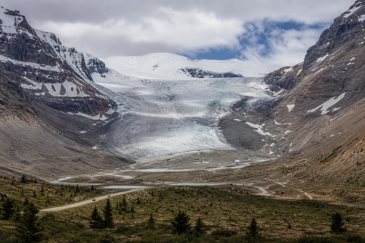 A guided Ice Explorer and visitors on the Athabasca Glacier below the peaks of the Columbia Icefield, illustrating what a ticket buys